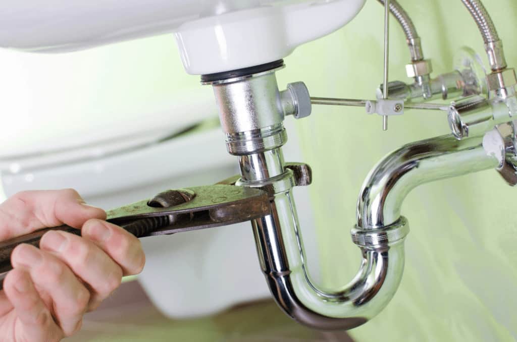 Fixing sink pipe with wrench